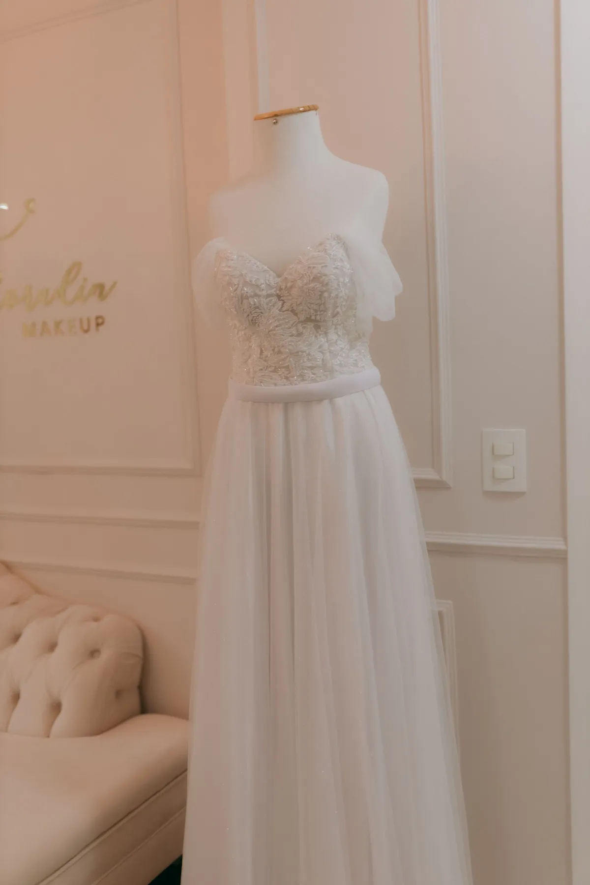 An ivory wedding gown on a dress form in a warm, softly lit room